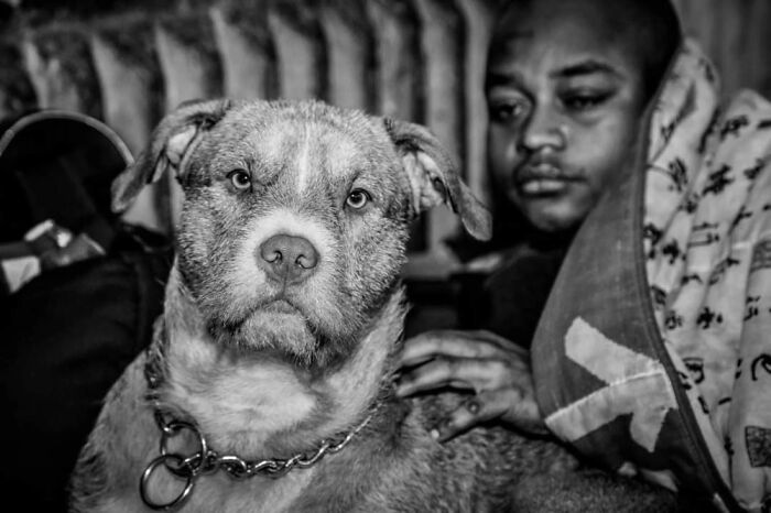 Black and white photo of a homeless person with their dog, capturing the bond shared in difficult living conditions.