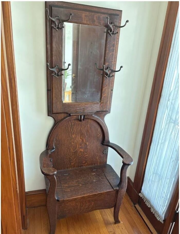 Antique wooden hall tree with mirror and hooks, a strange thing found in homes with hidden or haunted pasts.