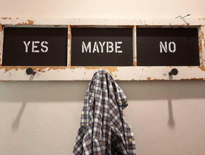 Coat hanging on a rustic wooden rack with yes, maybe, and no labels, illustrating tough when life gives you lemons advice.