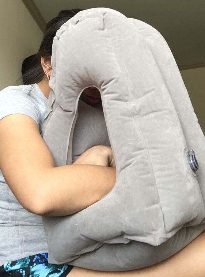 Person using a gray inflatable travel pillow for comfort, demonstrating in-flight essentials for a coach budget.