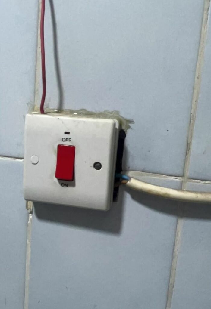 Old electrical switch with exposed wiring on tiled wall, an example of strange things found in homes with hidden pasts.