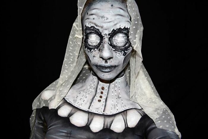 Horror-inspired makeup look with black and white face paint, textured details, and a sheer veil by talented makeup artists.
