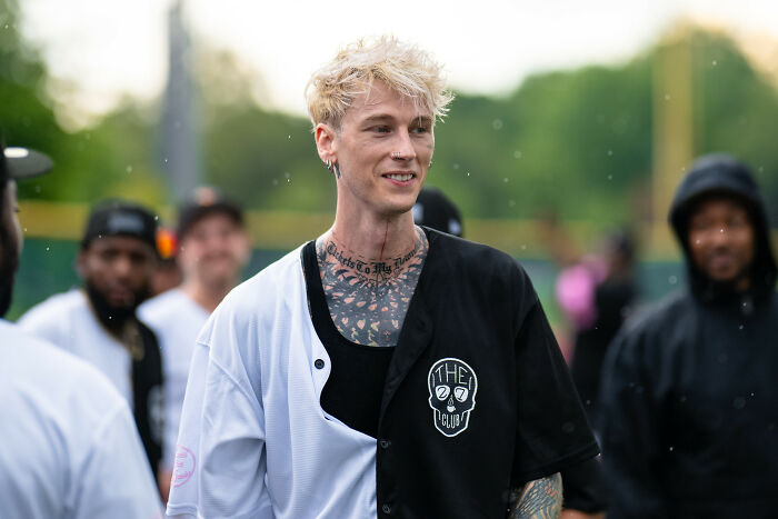 Young man with tattoos and a split black and white shirt socializing outdoors, reflecting middle class and Gen Z themes.