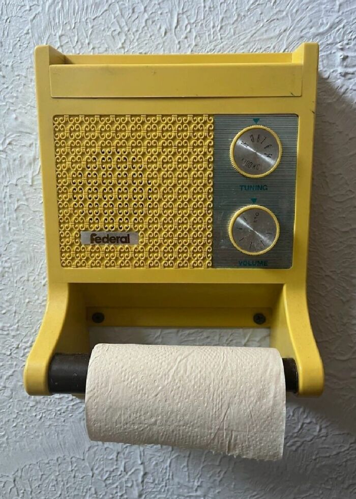 Vintage yellow radio toilet paper holder mounted on textured wall, a strange thing found in homes with hidden pasts.