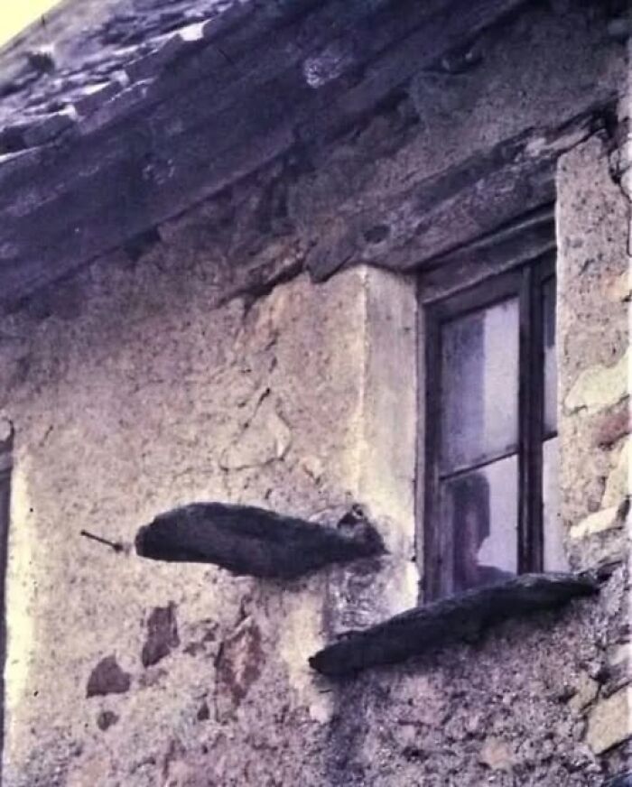 Old stone wall with a small window and dark wooden beams in a home with a hidden or haunted past.