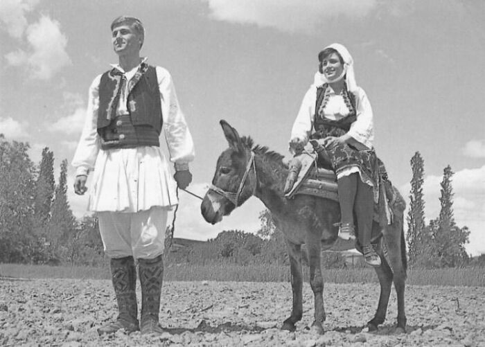 Black and white photo of a man and woman in traditional dress with the woman seated on a donkey, history uncaptured in textbooks.