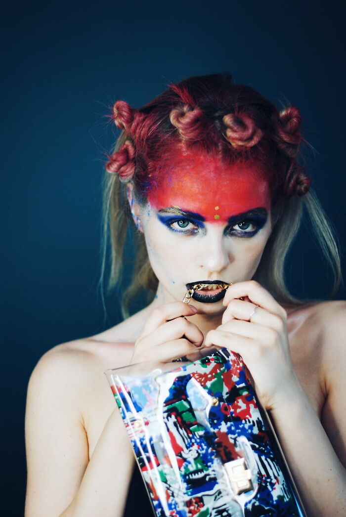 Creative makeup look with red face paint, bold eye makeup, and artistic hair styling by talented makeup artists.