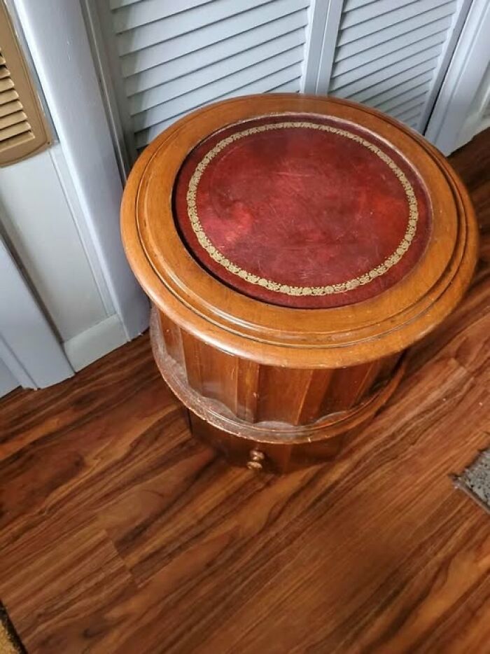 Round wooden furniture piece with worn red leather top, one of the strange things found in homes with haunted pasts.