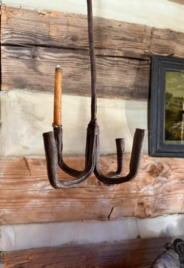 Rusty iron candle holder with one candle, hanging in a home with a hidden and forgotten past.