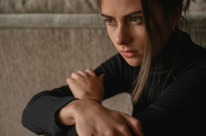 Young woman in black sweater looking upset, symbolizing family drama over graduate refusing to cancel trip. Young woman in black sweater looking upset, symbolizing family drama over graduate refusing to cancel trip.