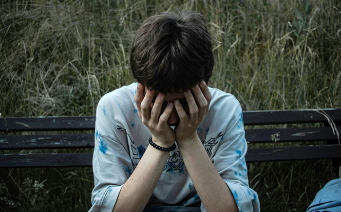 Teen sitting outside with head in hands, reflecting on being blamed for tempting after sneaking into roommate’s room to steal alcohol Teen sitting outside with head in hands, reflecting on being blamed for tempting after sneaking into roommate’s room to steal alcohol