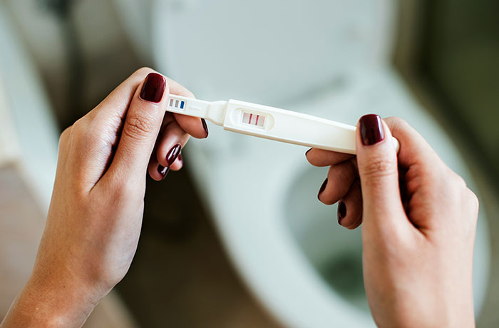 Hands holding a positive pregnancy test, symbolizing concerns about teen son and girlfriend pregnant on purpose.