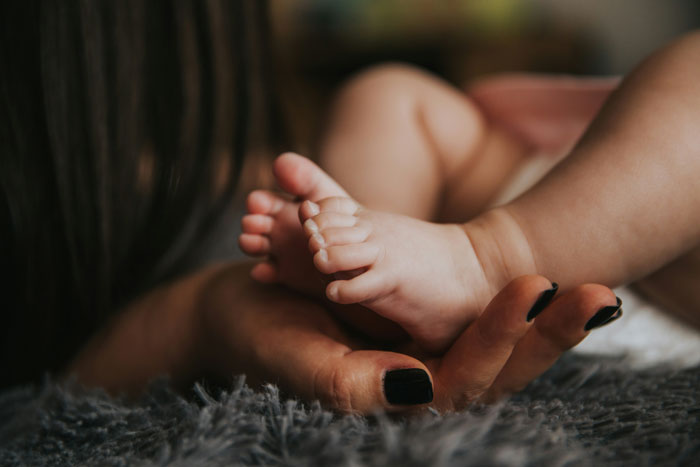 Close-up of woman holding baby feet, symbolizing openness to having kids and relationship challenges about marriage. Close-up of woman holding baby feet, symbolizing openness to having kids and relationship challenges about marriage.