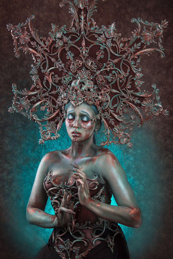 Intricate makeup look with metallic body paint and elaborate headpiece by a talented artist in a dramatic style.