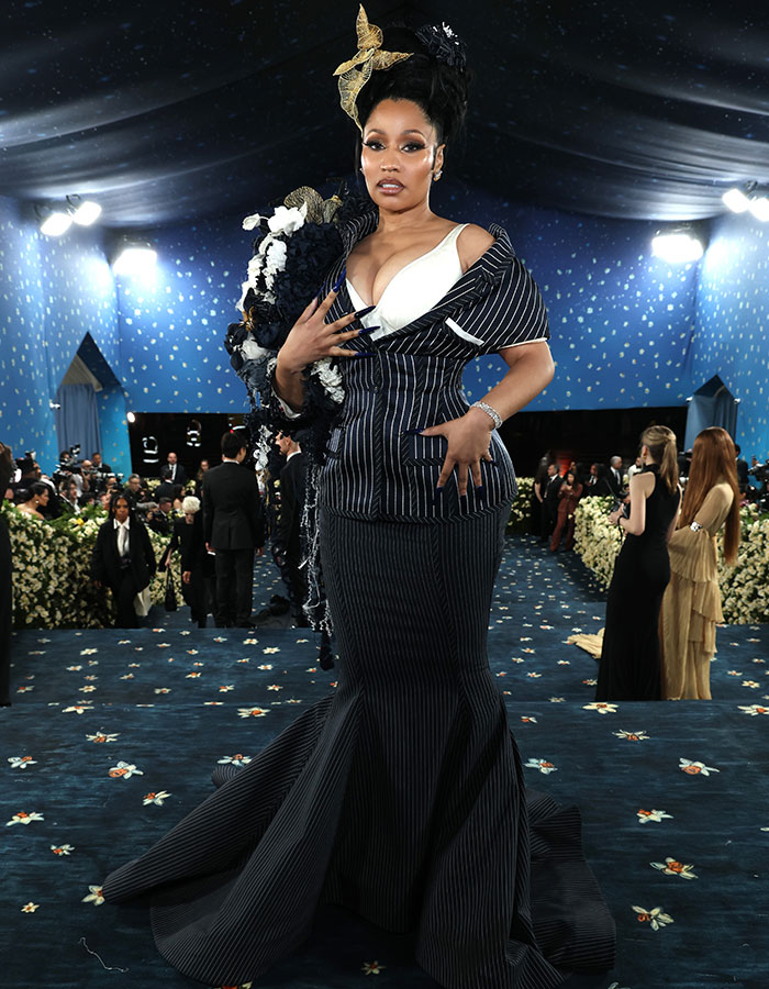 Celebrity posing in a dramatic striped gown with floral and bow details showcasing fashion fails at the Met Gala 2025 event.