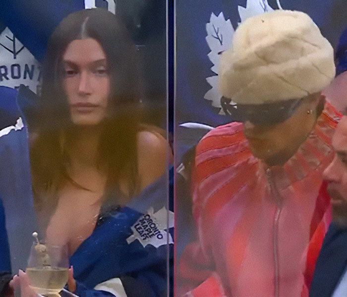 Hailey Bieber looking somber at a sports event while Justin Bieber wears sunglasses and a fur hat nearby.