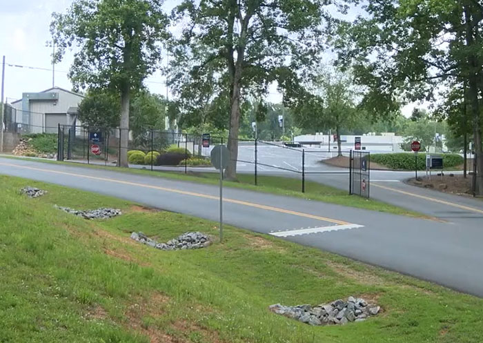 Entrance road to a Christian school campus surrounded by trees and fencing amid debate over teen girl expelled for trans prom date.
