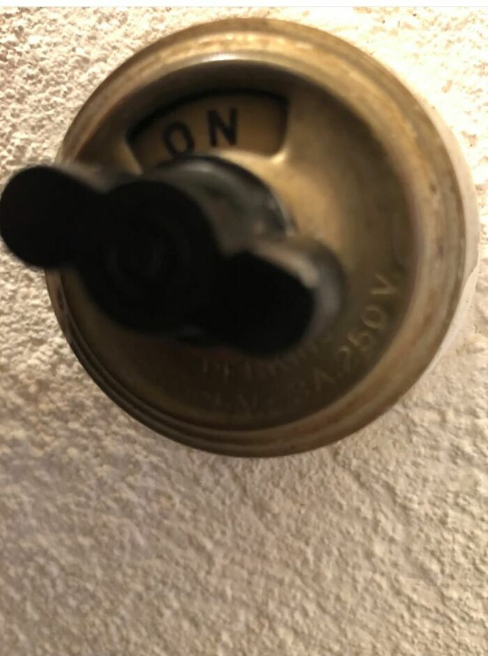 Old vintage electrical switch on textured wall, one of the strange things found in homes with hidden pasts.