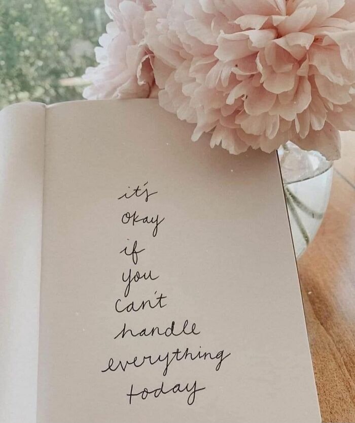 Handwritten motivation on a notebook page with soft pink flowers in a vase, showing cute and wholesome vibes.