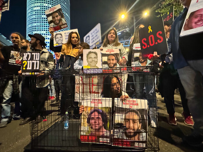 Protesters holding signs and photos in a powerful moment capturing the essence of humanity at IPA 2024 event.