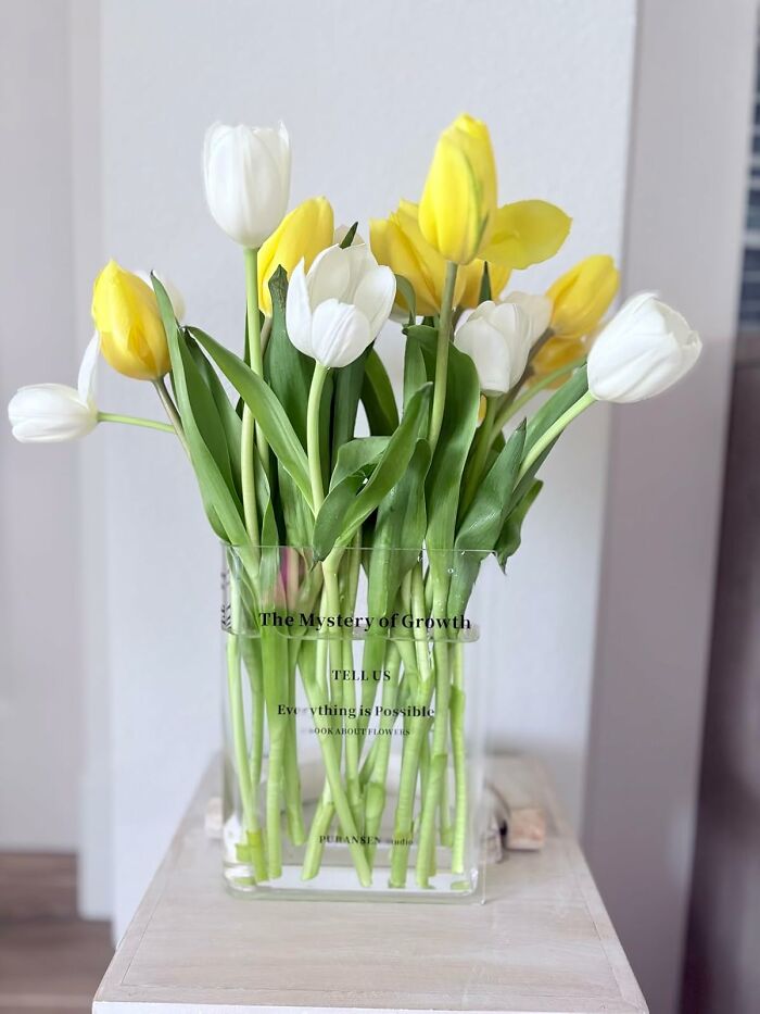 Yellow and white tulips arranged in a clear vase on a wooden surface, adding a happy place touch to home decor.