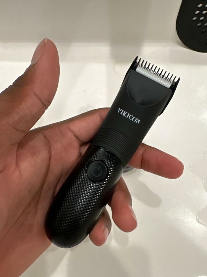 Hand holding a black grooming device designed for summer body care, helping with sweat and hair management.