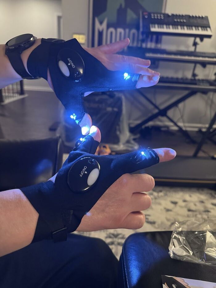 Hands wearing black LED gloves with fingers lit up in blue light, ideal for unique Father's Day gifts.