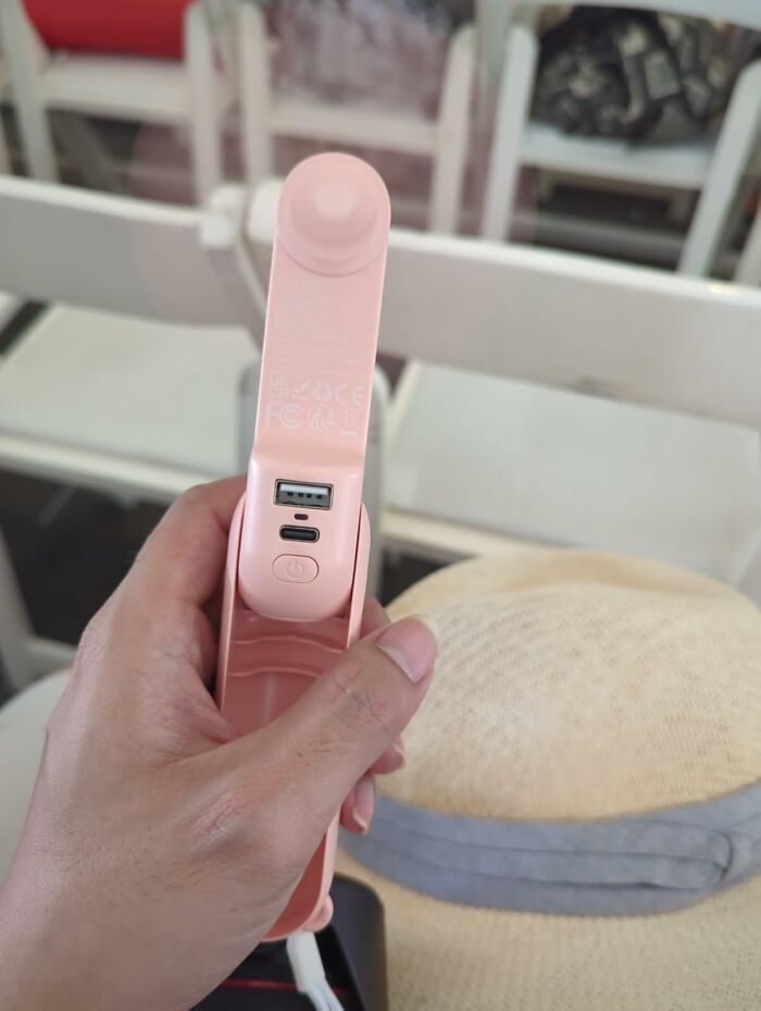 Hand holding a pink portable USB rechargeable fan, a viral summer essentials item to beat the heat.