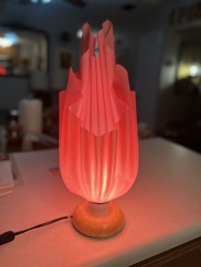 Red glowing thrifted lamp with a unique pleated design, showcasing a weird and wonderful vintage find.