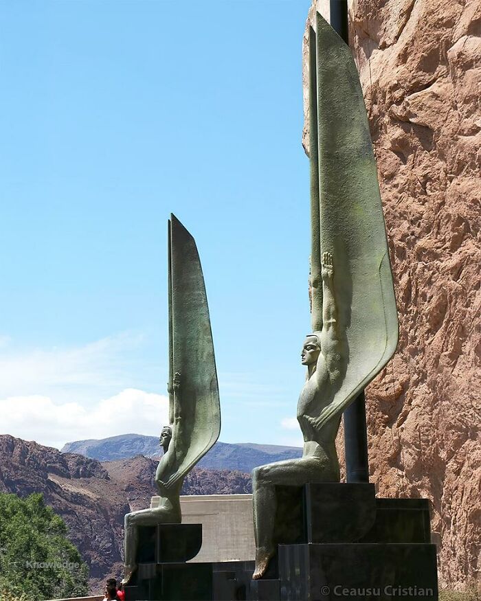 Bronze statues with wings on black pedestals against a rocky landscape, representing ancient history monuments.