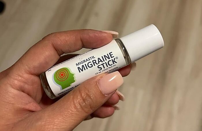 Hand holding a migraine stick, one of the everyday annoyances relief finds under 20 dollars for quick pain ease.