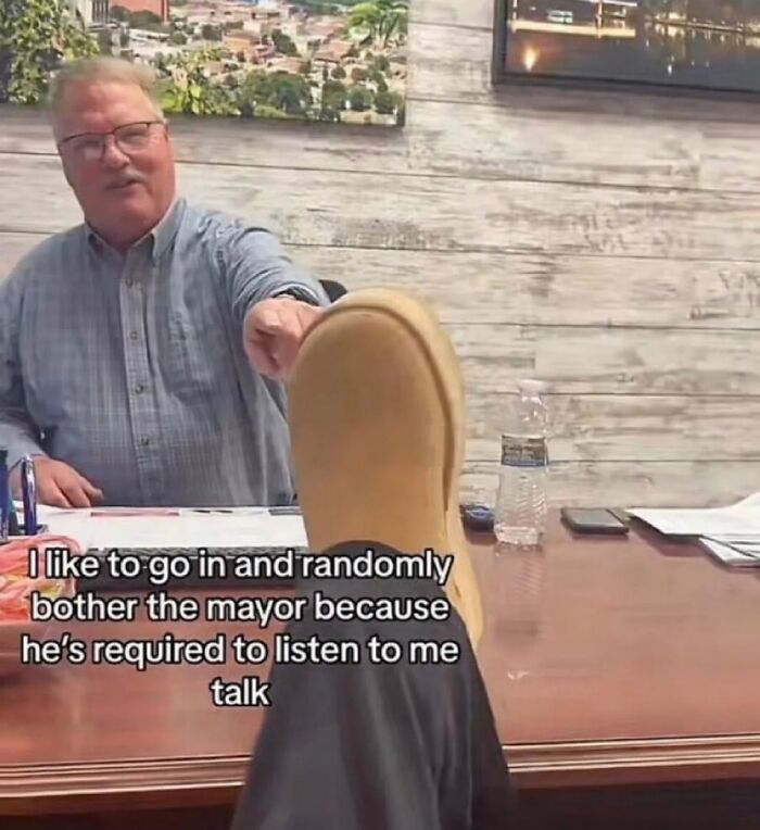 Man playfully putting boot on desk in office, chaotic meme humor for when life gets boring and random moments happen.