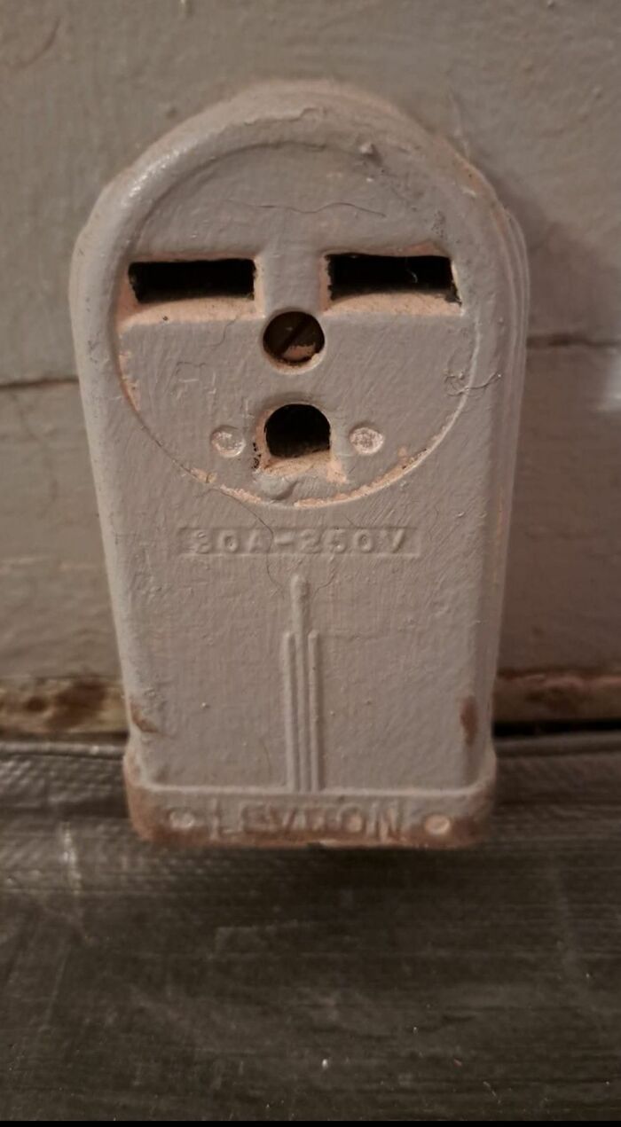 Old dusty electrical outlet with strange design found in homes with hidden or haunted pasts.