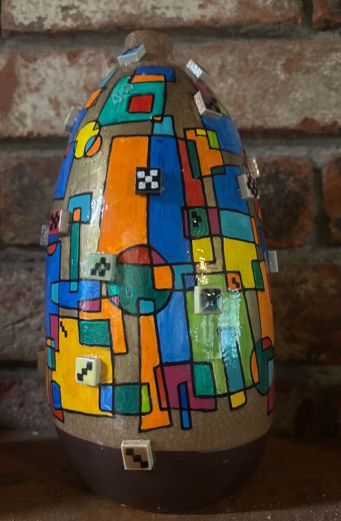 Colorful thrifted vase with geometric patterns and small attached tiles, a weird and wonderful vintage find for museum display.