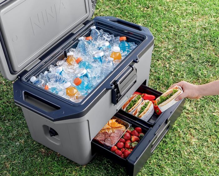 Large cooler with ice-cold drinks and a drawer filled with sandwiches, strawberries, and snacks for viral summer essentials.