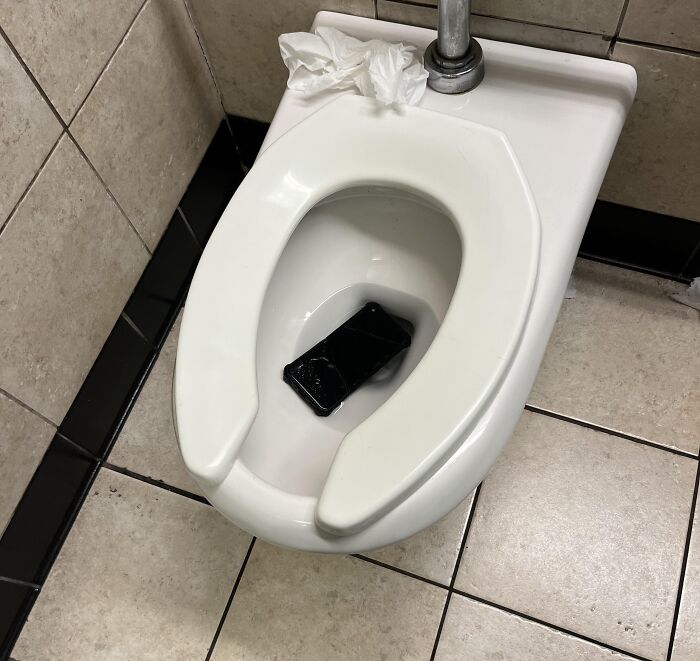 Toilet with a wet phone inside, illustrating a bad Friday the 13th moment people would warn you to hold their beer.