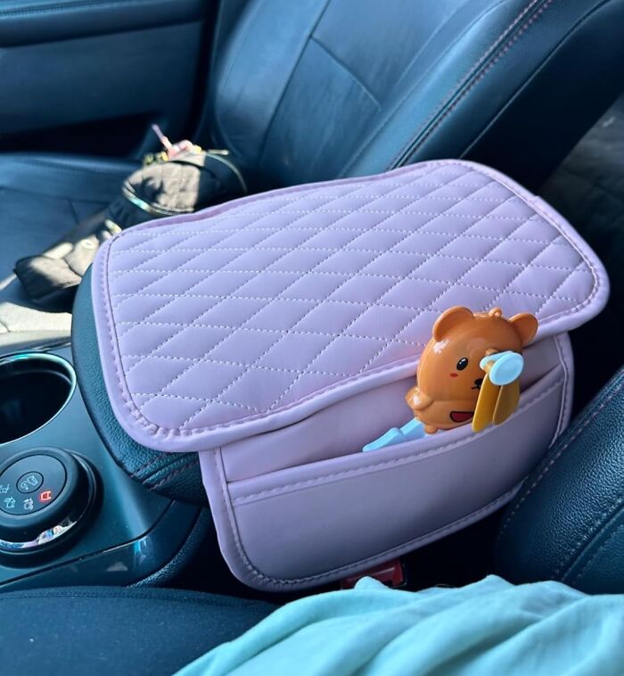 Quilted pink car accessory organizer on center console with a small toy, enhancing car interior style.