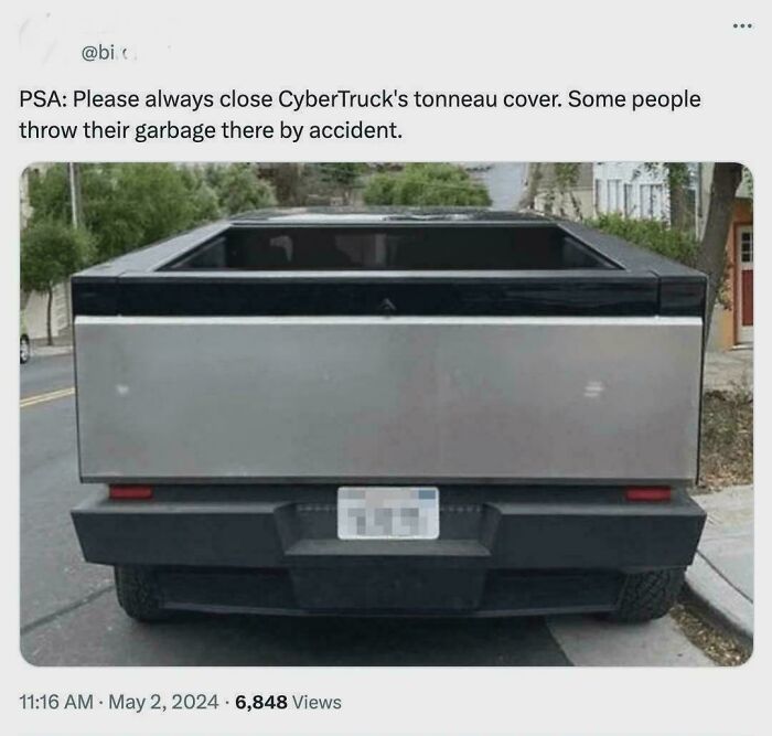 Rear view of a CyberTruck with an open tonneau cover, highlighting a street scene improved by wholesome vandals.