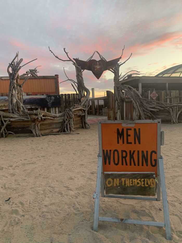 Wholesome vandals creativity shown in street art made from driftwood structures at sunset in sandy area.