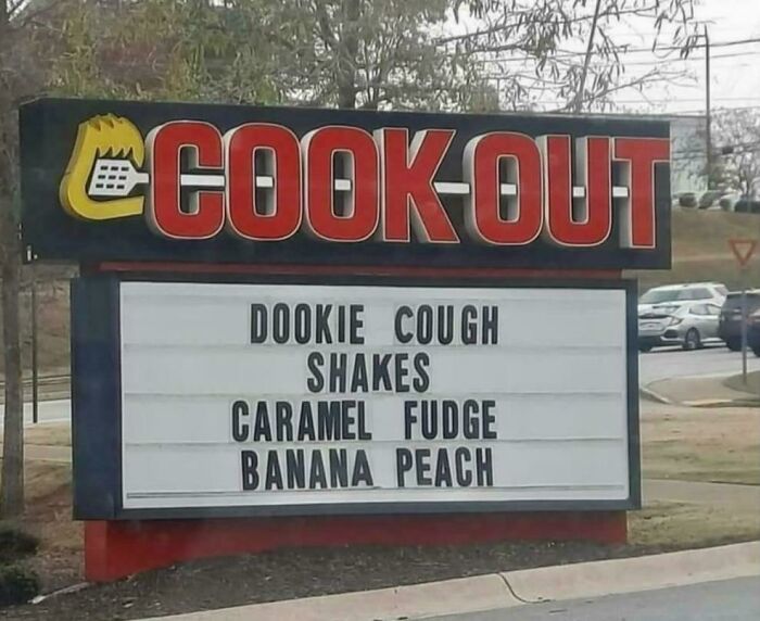 Cook Out restaurant sign humorously altered with funny shake flavors, showcasing wholesome vandalism on streets.
