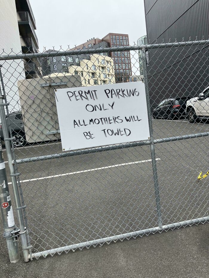 Permit parking only sign on chain-link fence in urban area showing wholesome vandalism improving streetscape.