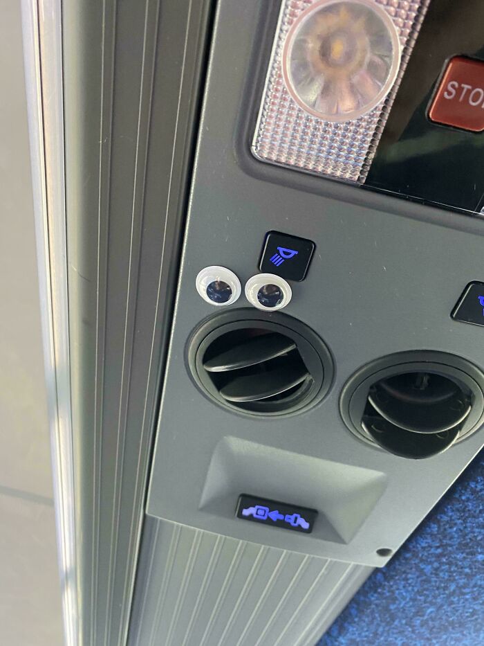 Googly eyes stuck above a vent on a vehicle ceiling, a wholesome vandal making streets look better.