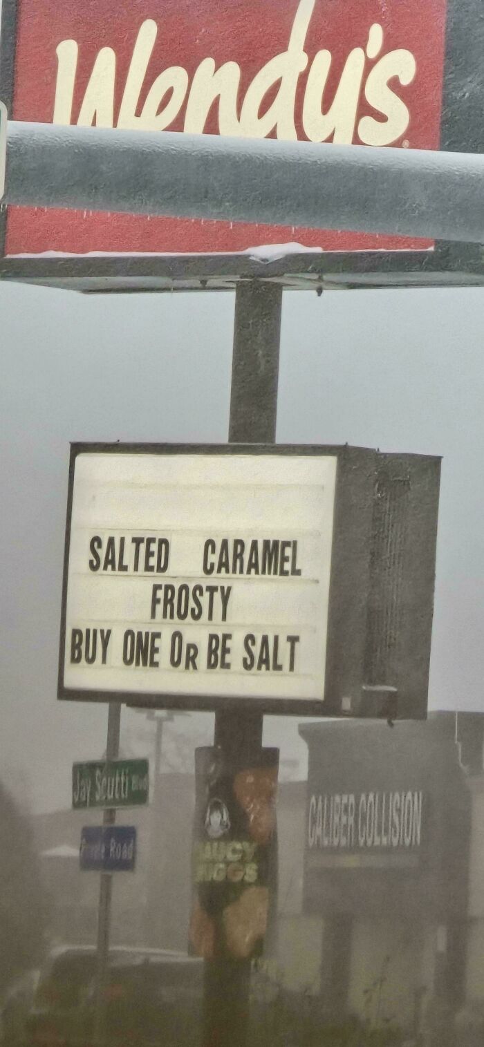 Wendy's street sign with a wholesome vandal message promoting salted caramel Frosty and humor on a snowy day