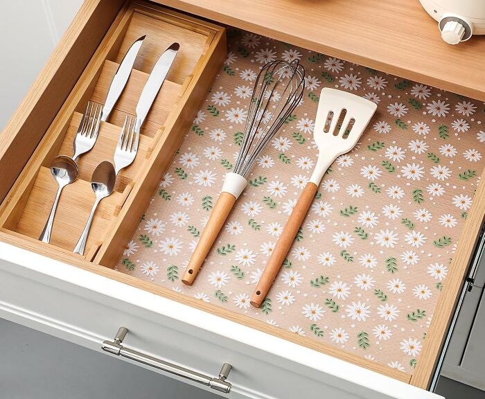 Kitchen drawer organized with cutlery and utensils on floral liners, enhancing your home as a happy place.