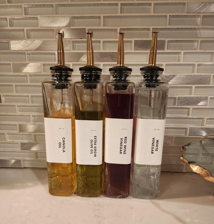Kitchen counter with bottles of canola oil, olive oil, red wine vinegar, and white vinegar organized for a happy home.