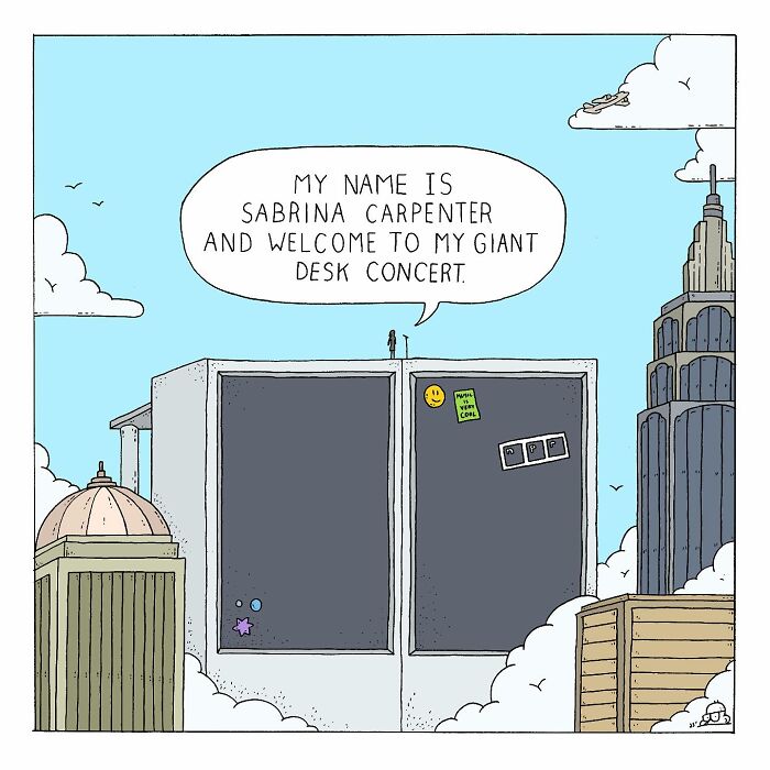 Comic panel showing a tiny figure announcing a giant desk concert atop two large desk drawers in a cityscape.