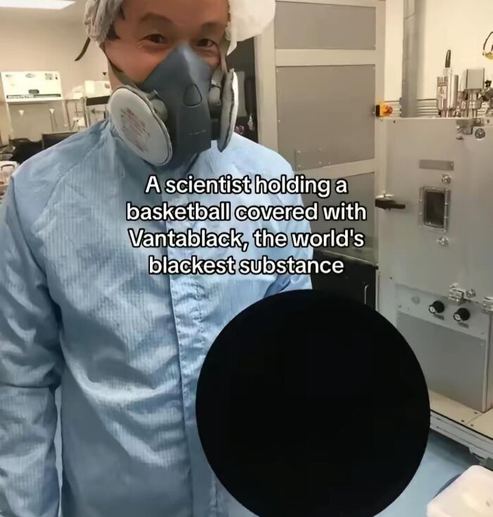 Scientist wearing protective gear holding a basketball covered with the blackest substance near Big Ben interior components.