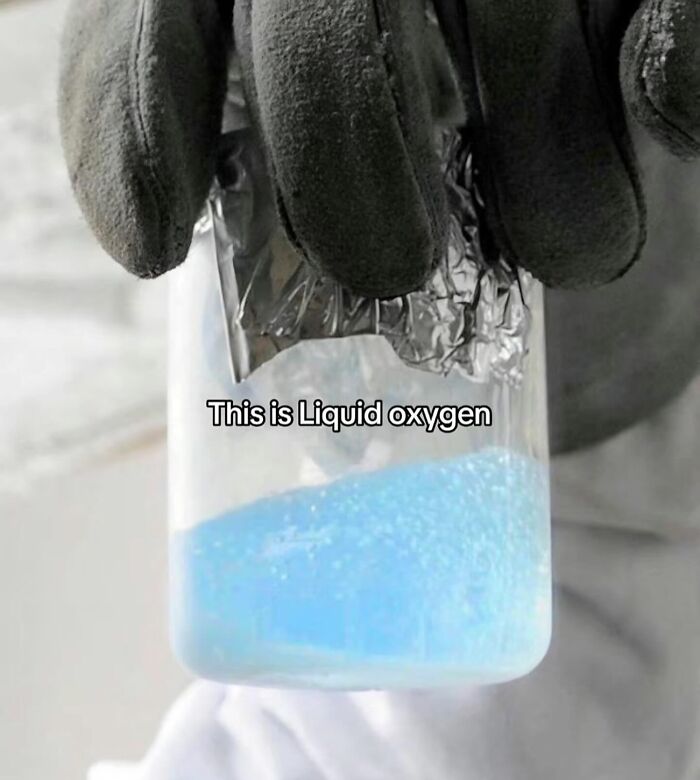 Close-up of a gloved hand holding a container with blue liquid oxygen inside, illustrating the inside of Big Ben concept.
