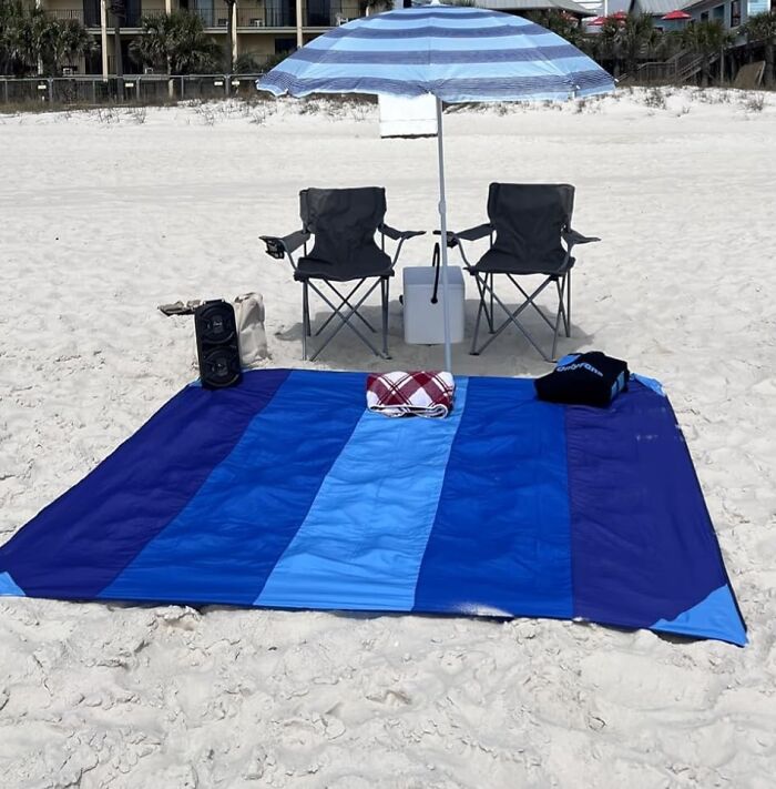 Beach setup with umbrella, chairs, cooler, and blanket, showcasing warm weather finds to help you thrive this season.
