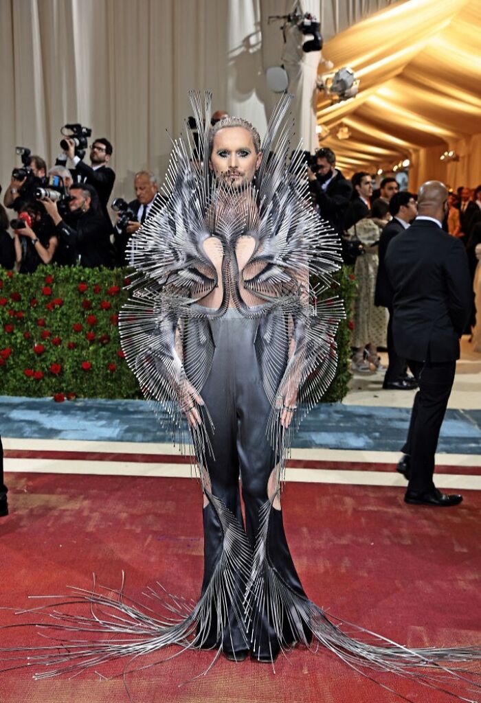 Celebrity wearing an elaborate avant-garde outfit at the Met Gala, showcasing a high fashion look that tried too hard.